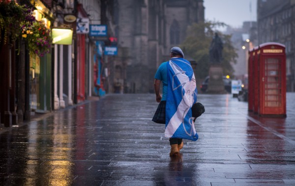 A Yes supporter walks through a rainy Edinburgh (Stefan Rousseau/PA)