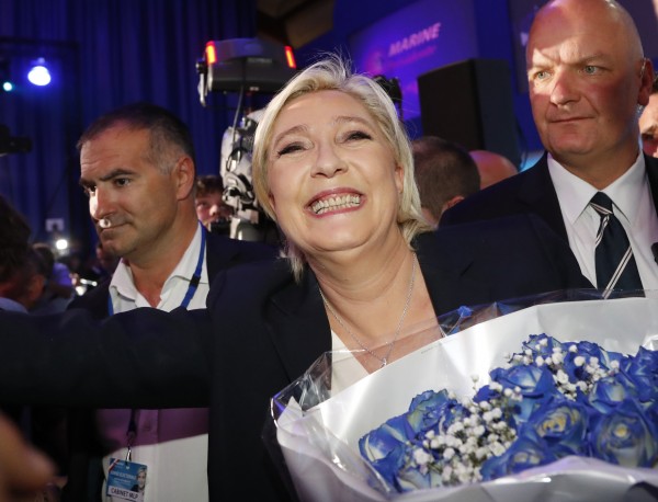 Far-right leader and candidate for the 2017 French presidential election, Marine Le Pen, surrounded by bodyguards, celebrates with supporters while holding a bunch of flowers after exit poll results of the first round of the presidential election were announced at her election day headquarters in Henin-Beaumont, northern France