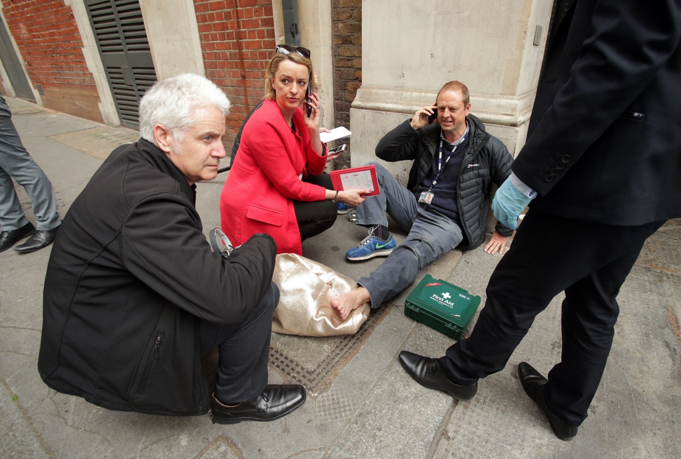 BBC's Laura Kuenssberg on the phone while her colleague, BBC cameraman Giles Wooltorton, sits on the floor after the car carrying Jeremy Corbyn ran over his foot as it arrived at the Institute of Engineering in London, where a Labour Party meeting is due to take place as they deal with the fallout from the sensational leak of its draft General Election manifesto.
